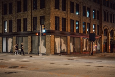 人们在夜间走在棕色混凝土建筑附近的人行道上